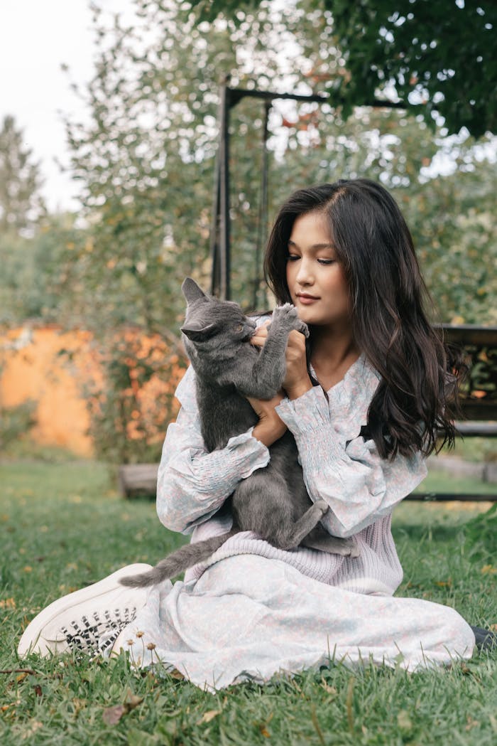 A young woman enjoying a serene moment outdoors while holding a gray cat.